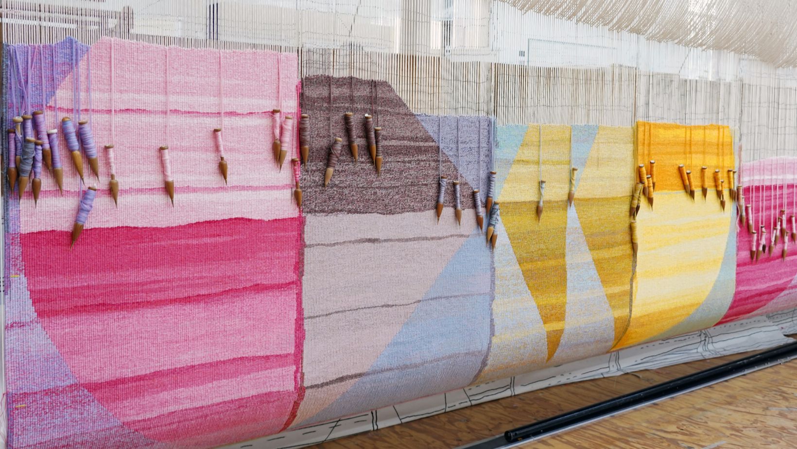 A closeup detail of a brightly coloured tapestry with geometic shapes on the loom at the Australian Tapestry Workshop.