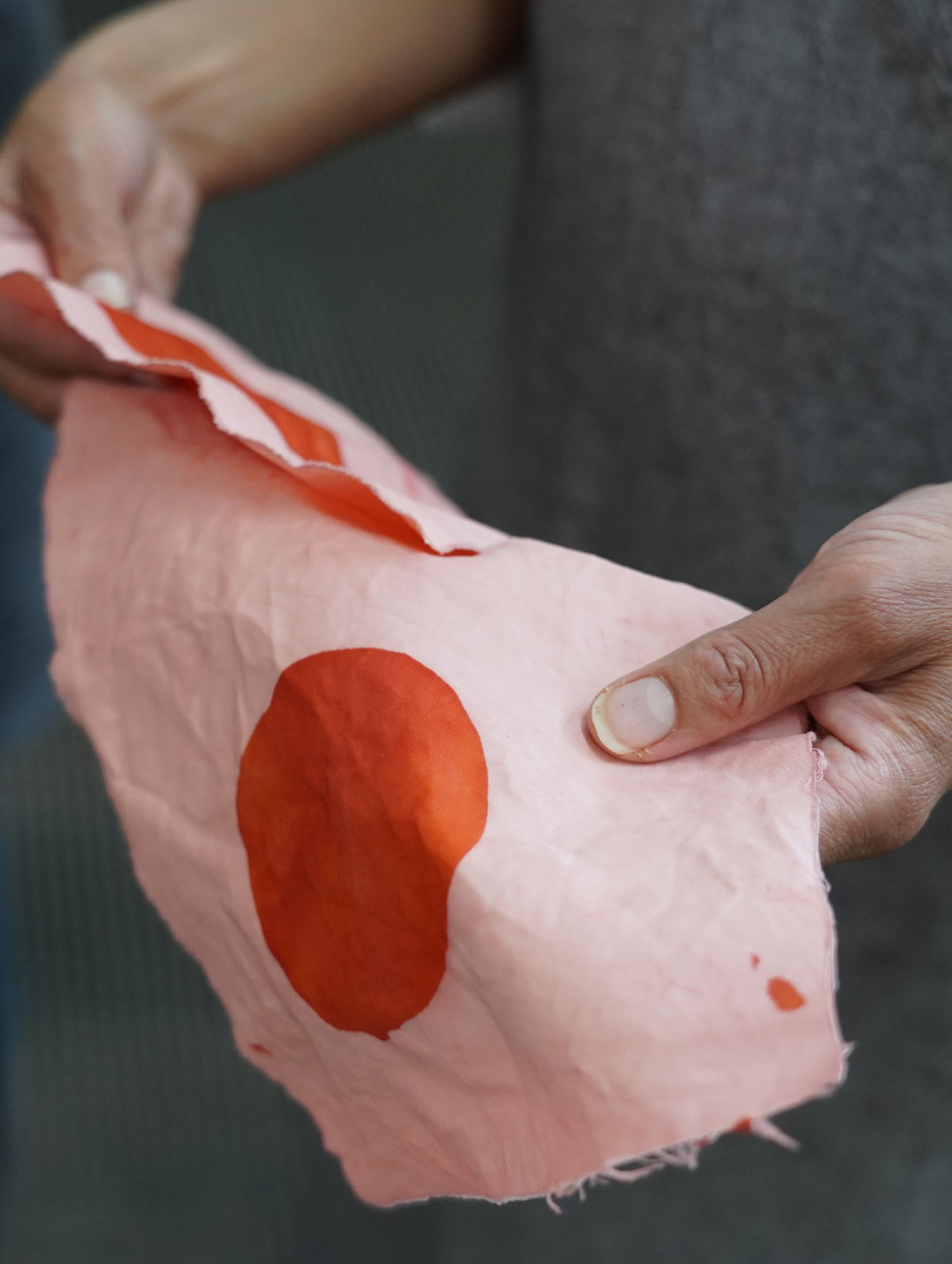 Artist's hands hold pieces of fabric in the ATW dye lab