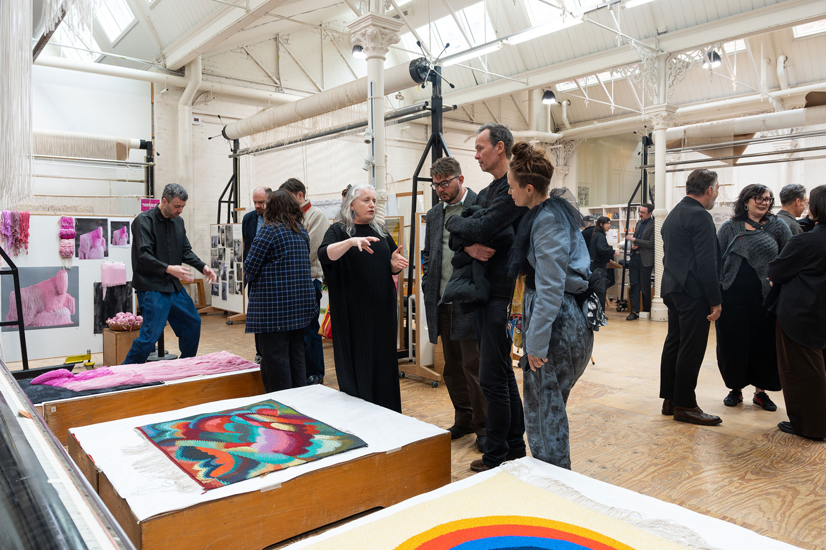 People chatting in a bright room with colorful textile art.