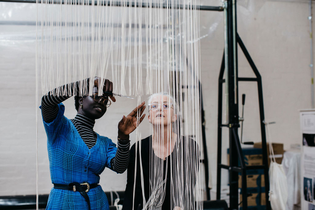 Atong Atem and Pamela Joyce cutting off the 'Portrait in July (4)' tapestry, designed by Atong Atem in 2021. Photograph: Marie-Luise Skibbe.
