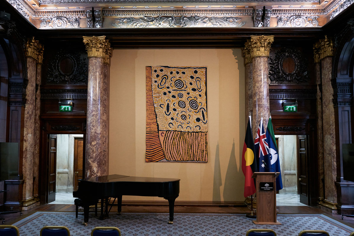 A tapestry hangs in a grand space with columns on either side.